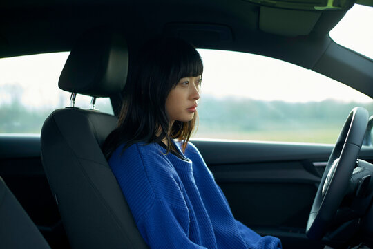 Woman in a blue sweater sits in a car, focused and looking out the window. Brandenburg, Germany