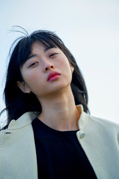 Woman with long hair and a pensive expression against a clear sky background. Brandenburg, Germany