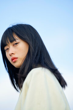 Portrait of a woman with long black hair against a clear blue sky background. Brandenburg, Germany