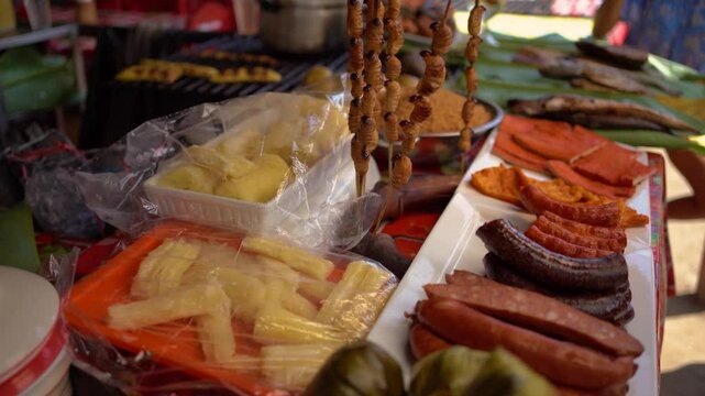 "Street food stall in Iquitos, Peru selling exotic dishes like alligator meat, suri larvae, and piranhas."