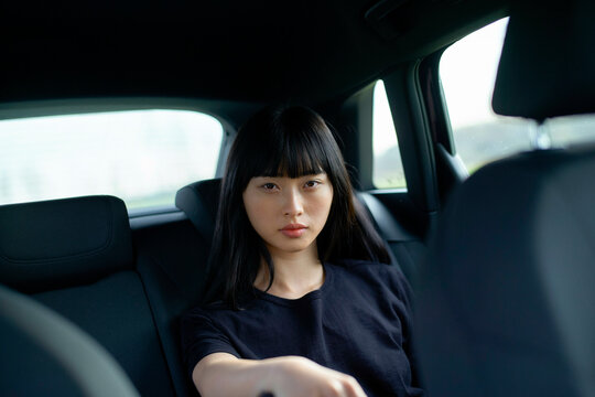 Young woman with serious expression sitting in the backseat of a car. Brandenburg, Germany