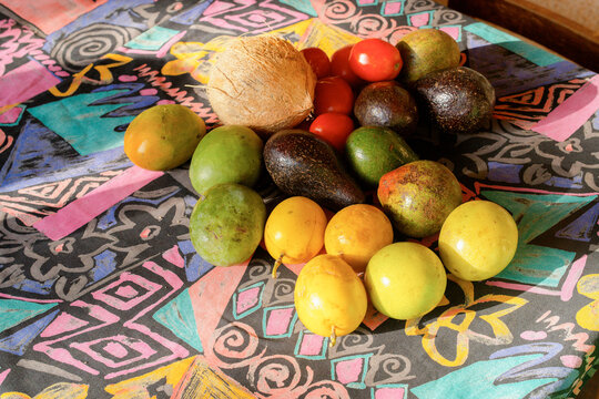 Assorted fruits including avocados, mangoes, and a coconut on a colorful patterned tablecloth. Tanzania, Africa