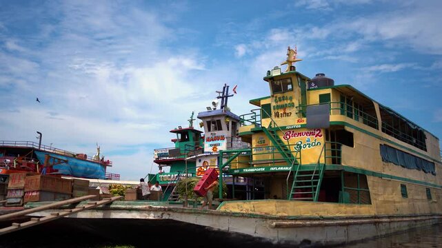 Workers loading bananas onto colorful cargo boats at the riverside port in Iquitos, Peru