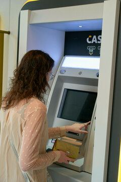 Woman using an ATM machine inside a modern banking facility. Brussels, Belgium