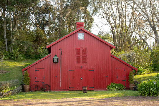 A vibrant red barn with trees in the background and a bicycle leaning against it. Auckland, New Zealand