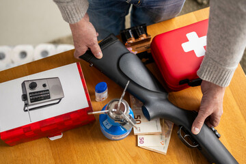 Person organizing survival gear on a wooden table with a radio and first aid kit. Preparing a survival weekend