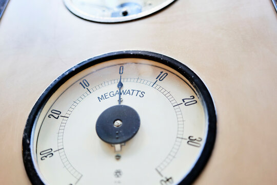 Close-up of an analog megawatt meter with a circular dial and black markings.