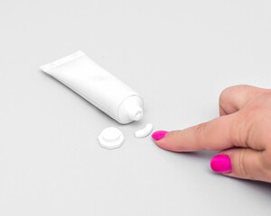 White tube of cream with a dollop and a finger pointing