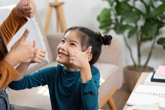 Positive Reinforcement and Happiness. A girl joyfully engages in a thumbs-up gesture while learning at home.