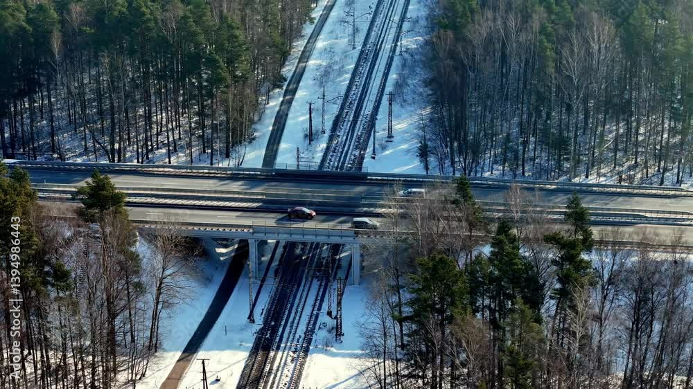 Poster aerial view of a snow-covered highway overpass intersecting with railway tracks below. surrounded by