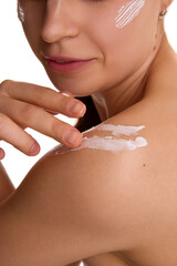 Cropped photo of young woman applying protecting cream on bare shoulder against white studio background. Soft and healthy skin. Concept of young and natural beauty, cosmetology treatment, cosmetic