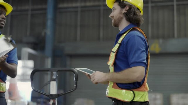 Warehouse workers working in the logistics industry, wearing hard hats, checking stock in a warehouse.