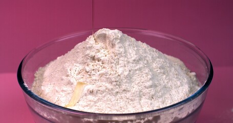 Egg falls into a bowl of flour in slow motion on a pink background