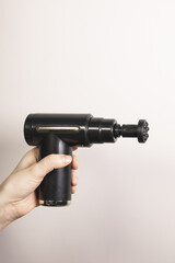 Vertical photo of woman holding percussion massage gun with small round head nozzle for joints. Physiotherapy, muscle recovery, self-massage tool. Healthcare. Close up.