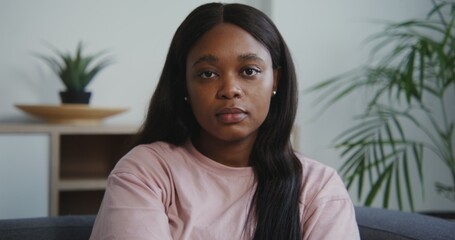 Beautiful young african american woman with long straight hair looks straight into the camera and...