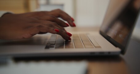 African american woman with red manicure typing on laptop, close-up
