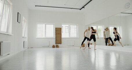 A guy and a girl of European appearance, dressed in sportswear, make synchronized movements while...