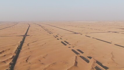 Aerial view of desert paved road buried by sand dunes. Dubai, United Arab Emirates. Daylight drone...