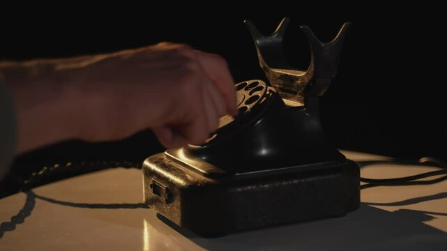 Person makes quick urgent 911 call. Man dialing numbers on an old vintage rotary style telephone. Retro phone with rotary dial. Fingers dialing a phone number. Vintage telephone old style, close up