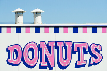 A pink donuts sign on the side of a truck with chimneys on top
