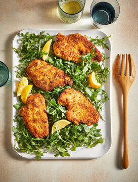 Chicken Paillard with arugula and lemon on table
