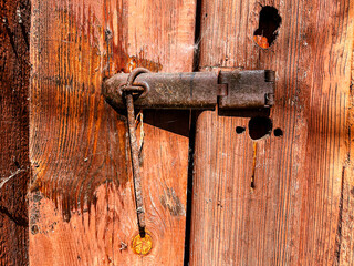 Weathered Wooden Door with Rusty Metal Latch and Visible Holes – A Close-Up Capturing Rustic Charm and the Effects of Aging on Timbers