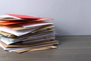 Post office. Stack of different paper envelopes on wooden table, closeup. Space for text