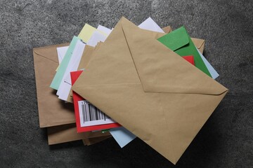 Stack of different paper envelopes on dark grey table, top view. Post office
