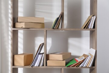 Different paper envelopes and parcels on wooden shelves in post office