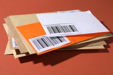 Different paper envelopes on red-brown background, closeup. Post office