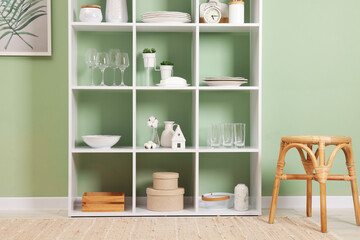 Shelving unit with dishware near olive wall indoors