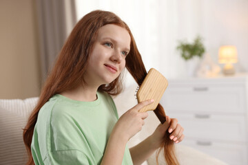 Beautiful teenage girl brushing her hair at home
