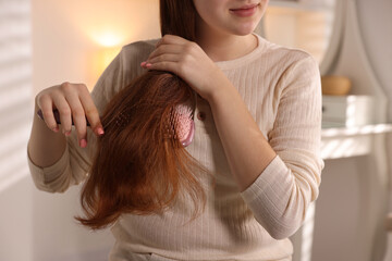 Teenage girl brushing her hair at home, closeup