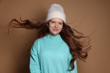 Beautiful teenage girl with freckles in hat on brown background