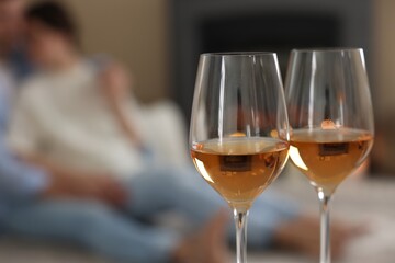 Couple near fireplace at home, focus on glasses of wine