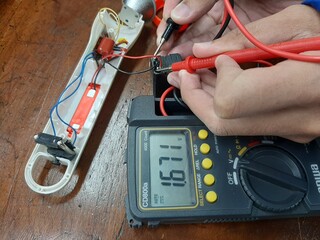 A portrait of a person using a multimeter to measure voltage in an electronic circuit.