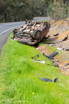 Crashed vehicle upside down on side of highway