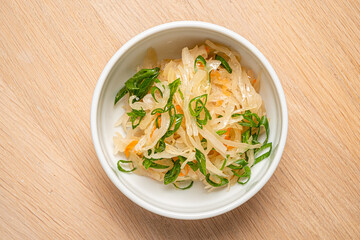 A colorful blend of shredded cabbage, carrots, and green onions sits on a wooden surface
