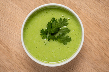 A vibrant bowl of creamy green soup showcases fresh herbs on top, perfect for a healthy meal