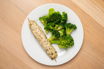 Enjoy a lovely chicken skewer with vibrant steamed broccoli on a wooden table