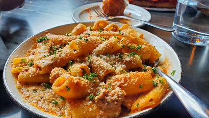 Creamy Rigatoni Pasta with Parmesan and Herbs in Restaurant Setting