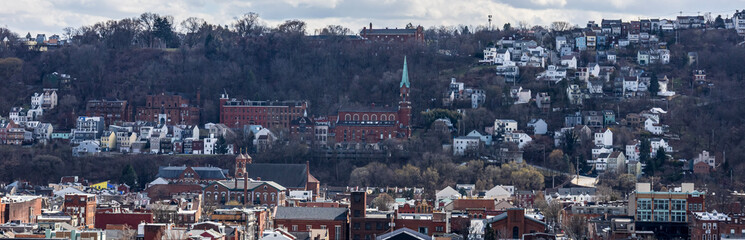 Pittsburgh, Pennsylvania, USA &ndash; March 18, 2024: A hillside view of Pittsburgh&rsquo;s South Side Slopes with dense residential housing and church steeples visible under a cloudy late-winter sky.