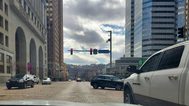 Pittsburgh, Pennsylvania, USA &ndash; March 18, 2024: View from a vehicle at a red light in downtown Pittsburgh, showing urban traffic, architecture, and cloudy skies on a late winter day.