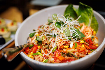 A bowl of food with a spoon in it. The food is a mix of vegetables and meat