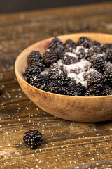 sour but ripe blackberries on the table with white sweet sugar, close up, side view