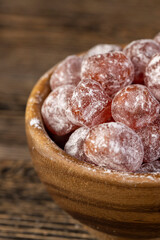sweet dehydrated candied fruits of kumquat in white powdered, close up in a bowl, side view
