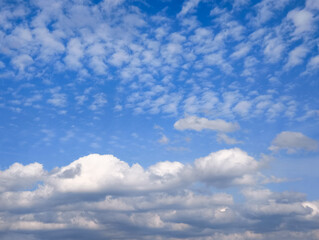 Naklejka premium Wispy white altocumulus clouds drifting across deep blue sky, presenting serene atmospheric landscape
