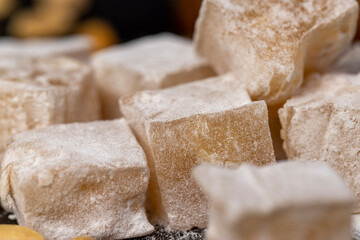 Turkish delight with peanuts closeup, scattered oriental sweets Turkish delight with peanuts on a board, side view