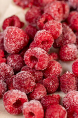 frozen red raspberries during their melting for dessert in winter close up