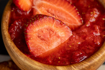 grated ripe strawberries in a wooden bowl, making a sweet dessert of strawberries, mashed without sugar, side view
